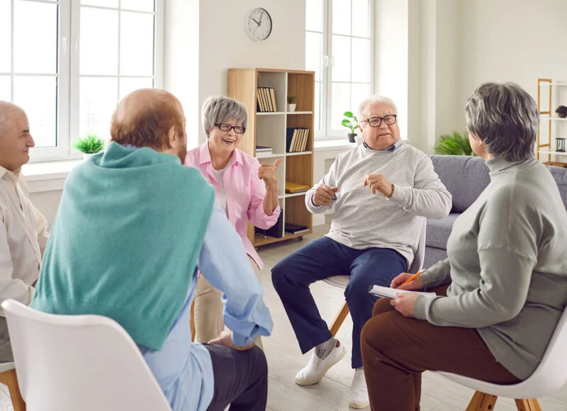 Older adults talking together in a circle of chairs